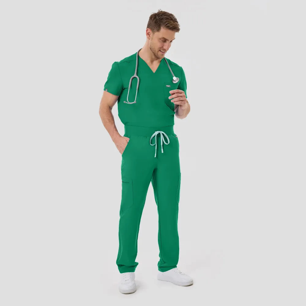 Male model full body in Indocyanine Green scrubs, angled downward gaze, white background.